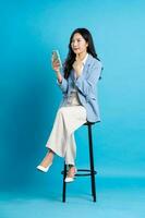 Asian businesswoman portrait sitting on chair, isolated on blue background photo