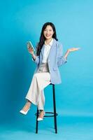 Asian businesswoman portrait sitting on chair, isolated on blue background photo