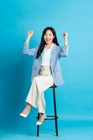 Asian businesswoman portrait sitting on chair, isolated on blue background photo