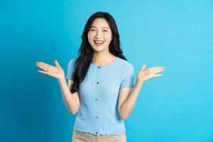 Portrait of a happy smiling asian girl posing on a blue background photo