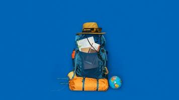 Tourist planning vacation with the help of world map with other travel accessories around. concept Luggage with accessory for travelers Vacation on Blue color background. Travel backpack photo
