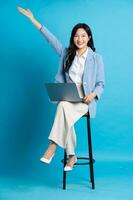 Asian businesswoman portrait sitting on chair, isolated on blue background photo