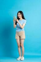 full body image of beautiful asian girl posing on blue background photo