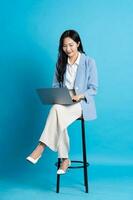 asiático mujer de negocios retrato sentado en silla, aislado en azul antecedentes foto