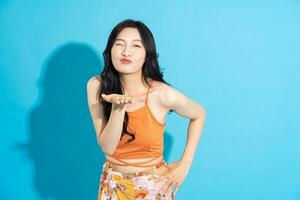 Portrait of a beautiful asian girl in a swimsuit smiling happily on a blue background photo