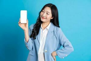 portrait of young asian businesswoman posing on blue background photo