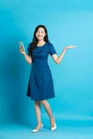 Portrait of beautiful woman in blue dress, isolated on blue background photo