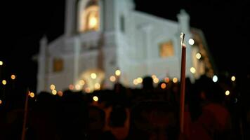 un' gruppo di persone in piedi nel davanti di un' Chiesa. fiamme sfarfallio durante il candela omaggio a il fest video