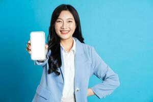 portrait of young asian businesswoman posing on blue background photo