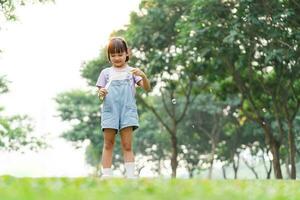 retrato de asiático niña jugando soplo burbujas foto