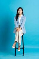 Asian businesswoman portrait sitting on chair, isolated on blue background photo