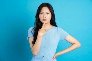 Portrait of a happy smiling asian girl posing on a blue background photo