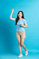 retrato de sonriente asiático mujer posando en azul antecedentes foto