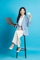 asiático mujer de negocios retrato sentado en silla, aislado en azul antecedentes foto