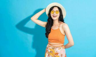 Portrait of a beautiful asian girl in a swimsuit smiling happily on a blue background photo
