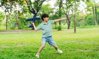 image of boy playing with toy plane in park photo