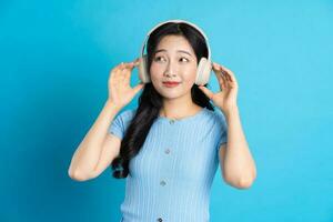 Portrait of a happy smiling asian girl posing on a blue background photo