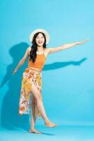 image of cheerful smiling asian woman in swimsuit, isolated on blue background photo