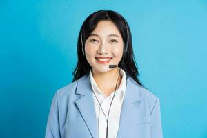 retrato de asiático negocio mujer posando en azul antecedentes foto