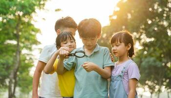 image of asian kids using magnifying glass in park photo