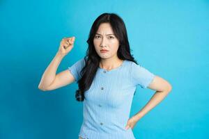 Portrait of a happy smiling asian girl posing on a blue background photo