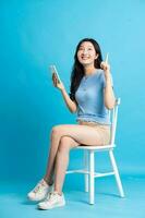 retrato de sonriente asiático mujer posando en azul antecedentes foto