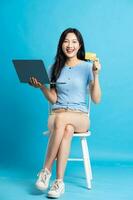 Portrait of smiling asian woman posing on blue background photo