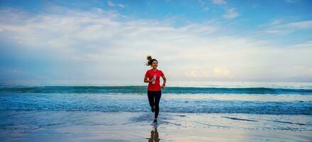 chica corriendo entrenamiento trotar en la playa por la mañana. relájate y feliz corriendo en el mar. en verano foto