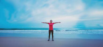 Asian women running workout jogging on the beach in the morning. extend the arms relax. photo