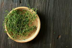 Green Thyme Herbs in a Rattan Bowl on Wooden Table. photo