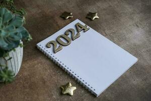 Blank notepad mockup and 2024 gold colored numbers. Wish list and goals for 2024 photo