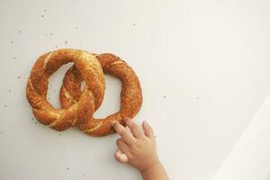 parte superior ver de niño mano recoger turco rosquilla simit en mesa foto