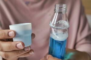 women hand hold a mouthwash liquid container photo