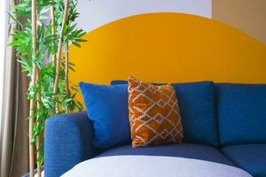 modern blue color sofa with pillows in living room against orange color wall photo