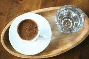 top view of hot coffee with bubble and glass of water on table photo