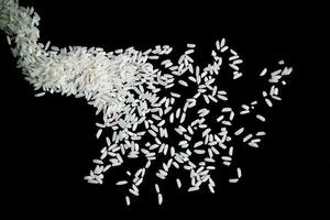 salpicaduras de arroz blanco crudo sobre fondo negro. explosión de arroz crudo. foto