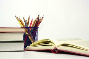 Crayon or colored pencils in box and the book placed in the blurred background. Knowledge and education concept. photo