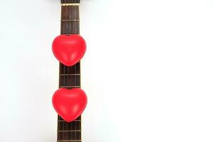 acústico guitarra cuello y rojo corazón en contra blanco antecedentes. amar, relajarse y música concepto. foto