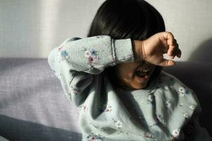 un trastornado niño niña cubrir su cara con mano foto