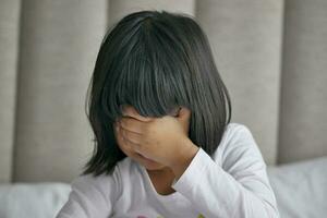 a upset child girl cover her face with hand photo