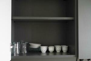 blanco platos y bochas en cocina gabinete. foto
