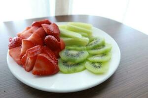 Ripe half kiwi fruit and strawberry on a plate photo