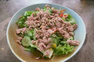 spoon pick tuna salad from a bowl on table photo