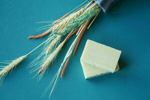 Homemade natural soap bar and dry flower on green background photo