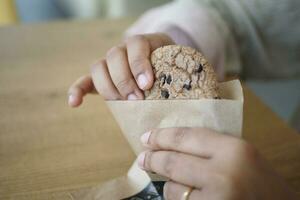 women hand taking cookies out from a paper packet photo