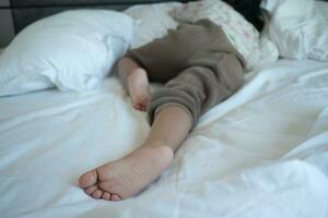 un niño dormido en cama descalzo foto