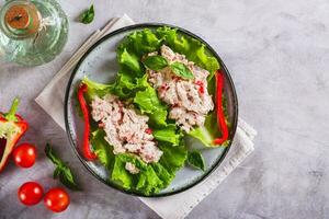 Canned tuna salad with vegetables on lettuce leaves on a plate top view photo