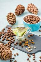Fresh pine nut oil, nuts in a bowl and on a slate board. Remedy for insomnia and detox food. Vitamins and health. Vertical view photo