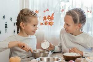 Treats and preparations for the celebration of halloween. Two girls prepare halloween cookies in the dough for baking in the kitchen. photo