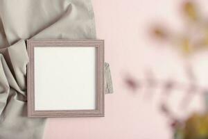 Empty photo frame and blurred branch on gray pink background top view